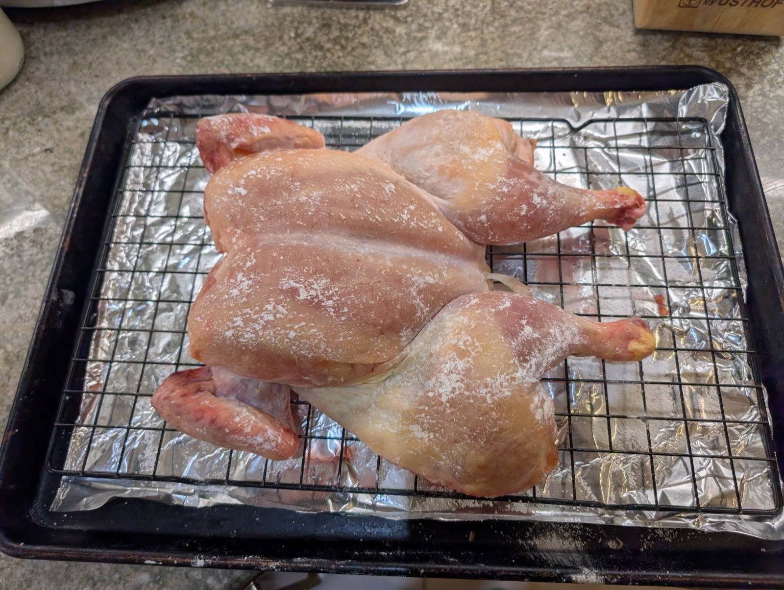 Spatchcocked chicken salted and resting on a rack